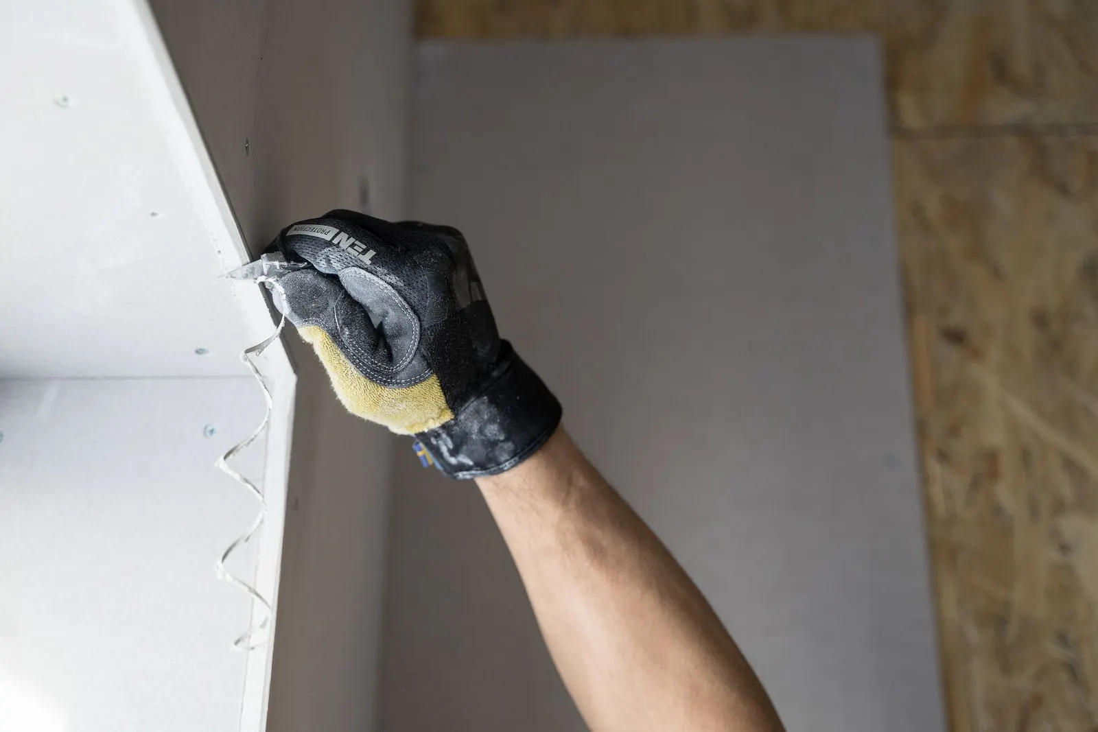 Gloved hand smoothing joint compound on a drywall seam